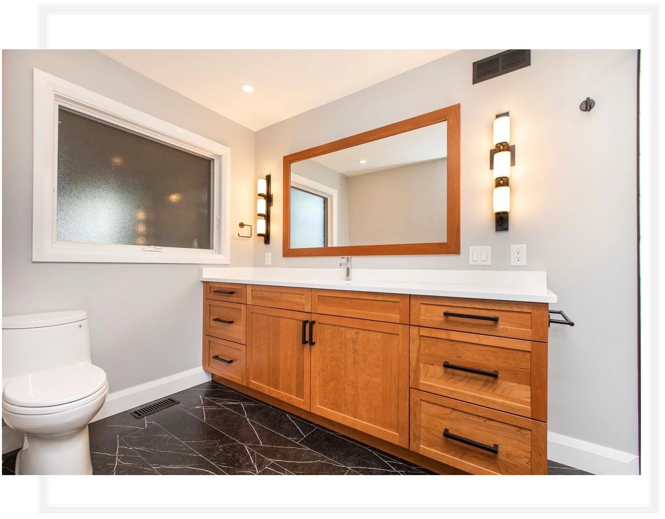 Bathroom Renovation – Original Framed Photograph Bathroom with a long wood vanity, a white countertop, a wood-framed mirror and dark marble-look floor tile